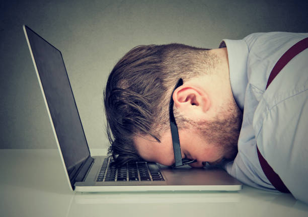 A frustrated man with his head on a laptop keyboard, symbolizing data loss stress.