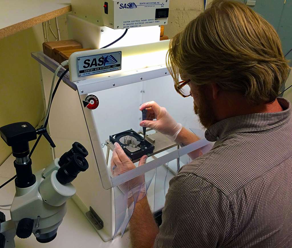 Technician performing data recovery on a hard drive in a cleanroom